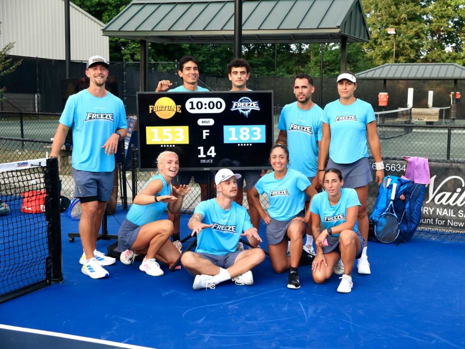 Players posed around a portable scoreboard on an outdoor court.